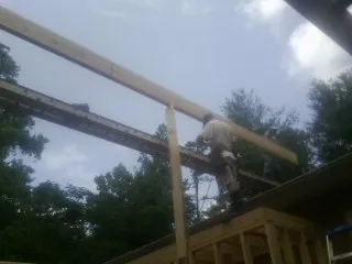 Carpenter setting a ridge beam over a new addition frame — Ice Dam Removal by Roofing Brothers in Huntsburg