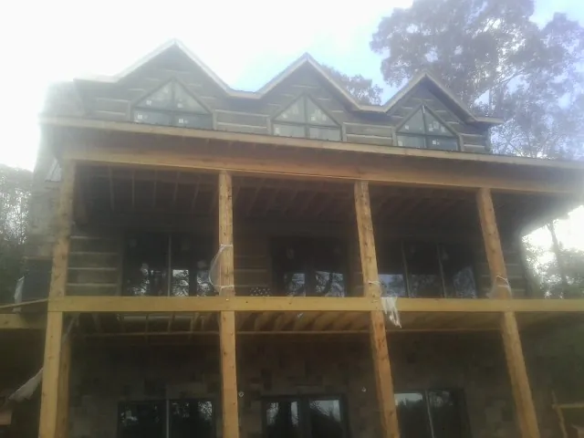 Dormers and porch framing on a large log home under construction — Roof Coating work by our crew in Huntsburg