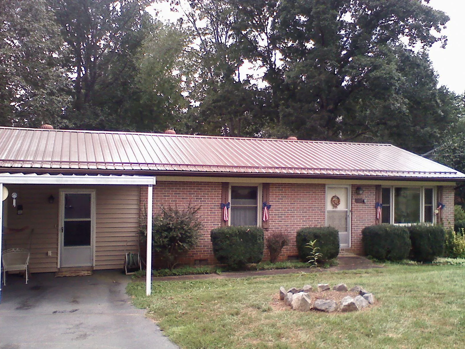 Bronze metal roof and carport on a brick ranch home — Roof Repair work by our crew in Huntsburg