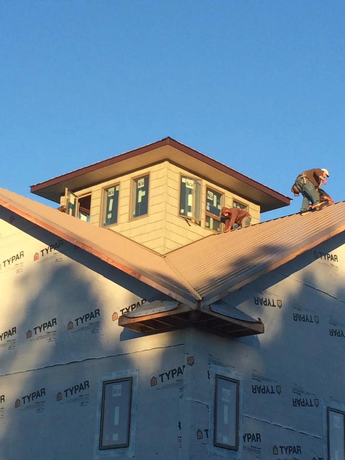 Roofers working around a rooftop cupola on a new metal roof at sunset — Roof Waterproofing in Huntsburg by Roofing Brothers